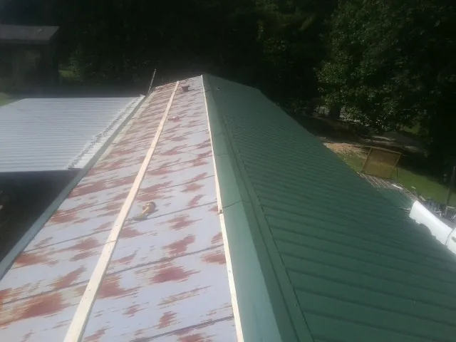 Old rusted panels beside newly installed green metal roofing — Wind Damage Roof Repair by Roofing Brothers in Billerica