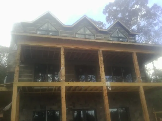 Dormers and porch framing on a large log home under construction — Roof Coating work by our crew in Billerica