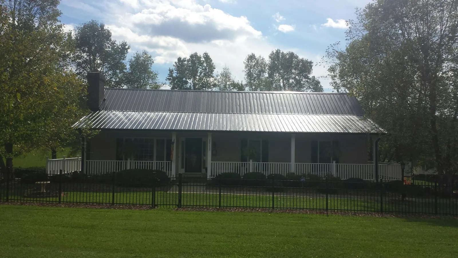 Gray metal roof on a brick ranch with a full width front porch — Gutter Guard Installation work by our crew in Billerica