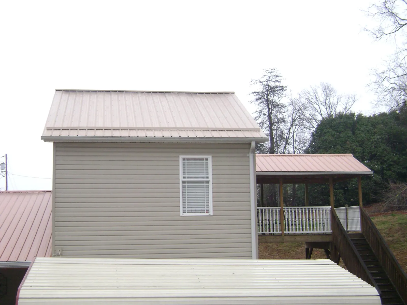 Tan metal roofs on a two story addition and attached porch, from a Roof Replacement job in Billerica