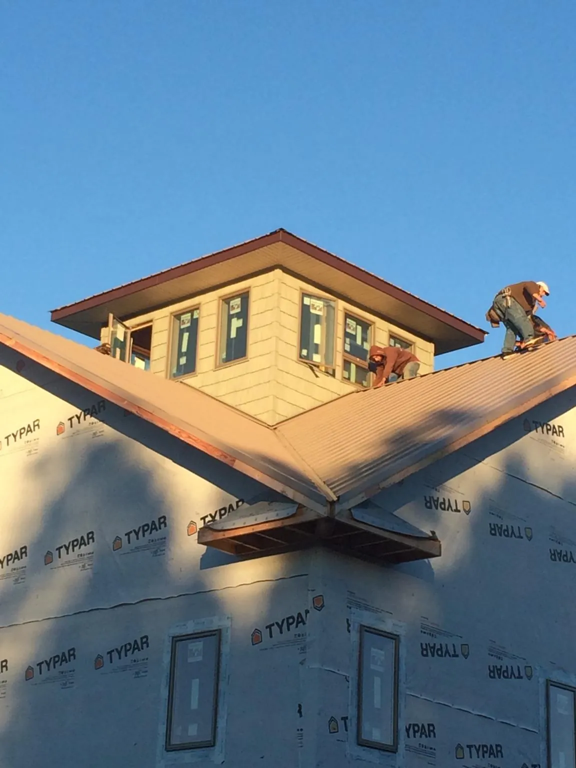 Roofers working around a rooftop cupola on a new metal roof at sunset — Roof Waterproofing in Billerica by Roofing Brothers